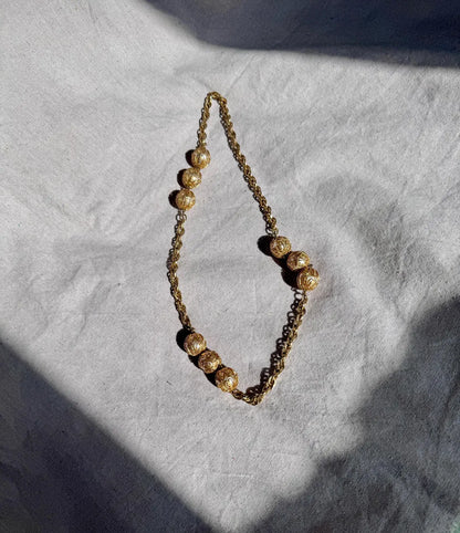 Gold beaded necklace on a textured white surface